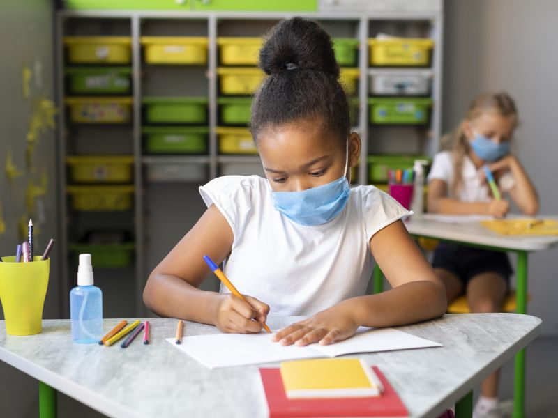 girls with mask writing in notebook