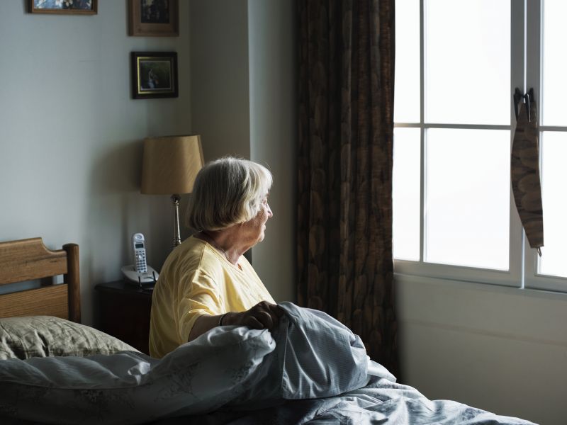 older woman sitting on bed alone